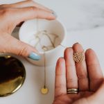 Woman holding delicate gold pendant, ideal for showcasing jewelry elegance.